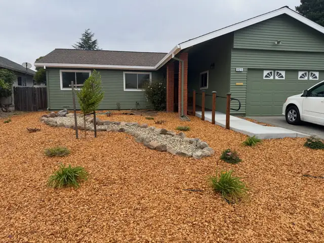 Petaluma home with new green vinyl siding, wood-railed entry ramp, and landscaped front yard with river rock and mulch