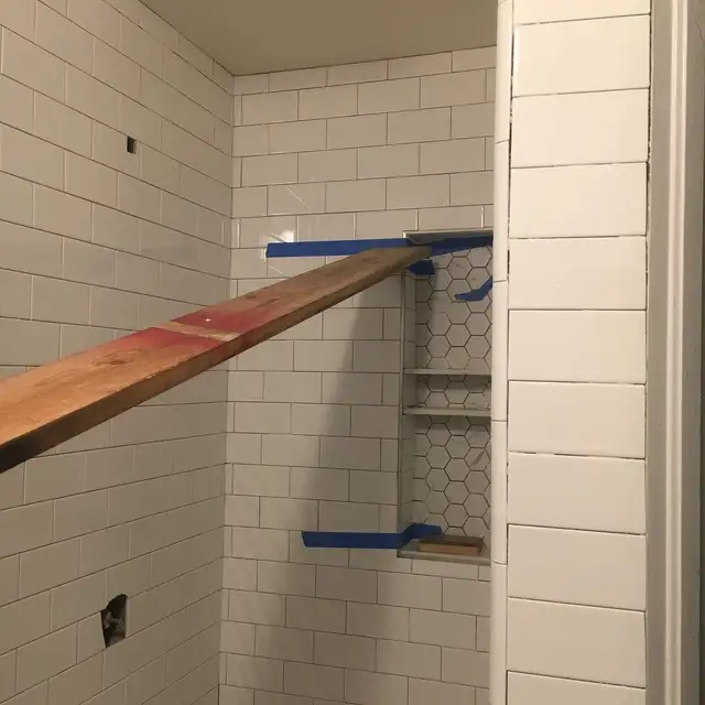 Subway tile shower under construction in Santa Rosa with wood bracing holding Schluter corners at a hexagon tile niche
