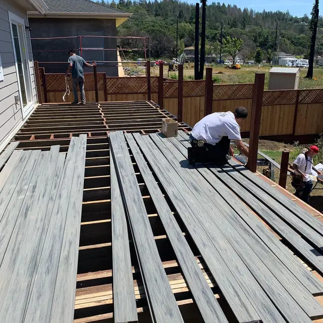 Workers installing gray composite decking over wood joist framing on a large elevated deck in Santa Rosa