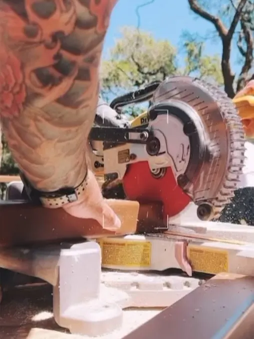 Worker cutting composite decking boards with a miter saw on a large Trex deck build in Santa Rosa