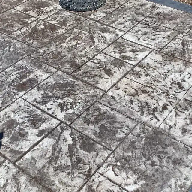 Close-up of stone-pattern stamped concrete slab with a metal utility cover, Santa Rosa golf cart garage project