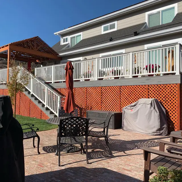 Second-story composite deck with white railing and staircase down to a brick paver patio in Santa Rosa
