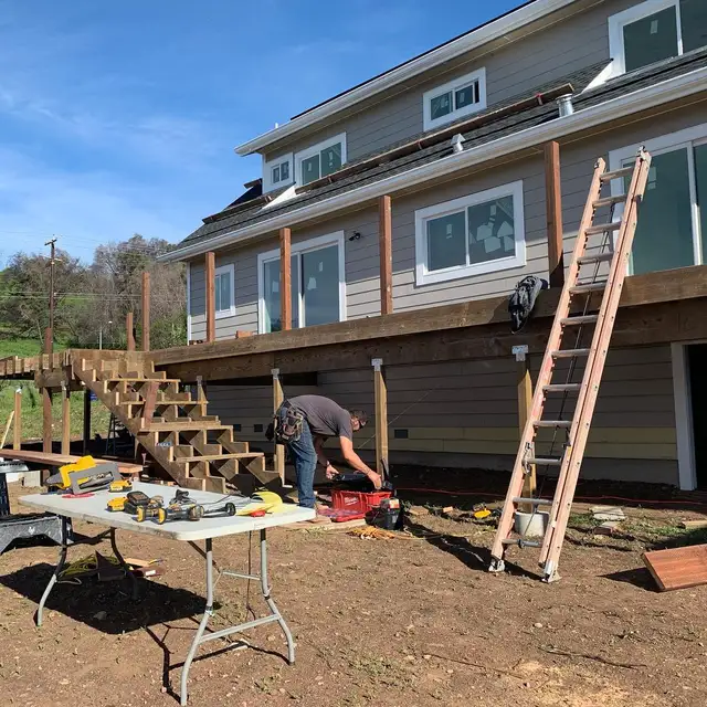 Worker framing an elevated wood deck and staircase on a two-story Santa Rosa home rebuild
