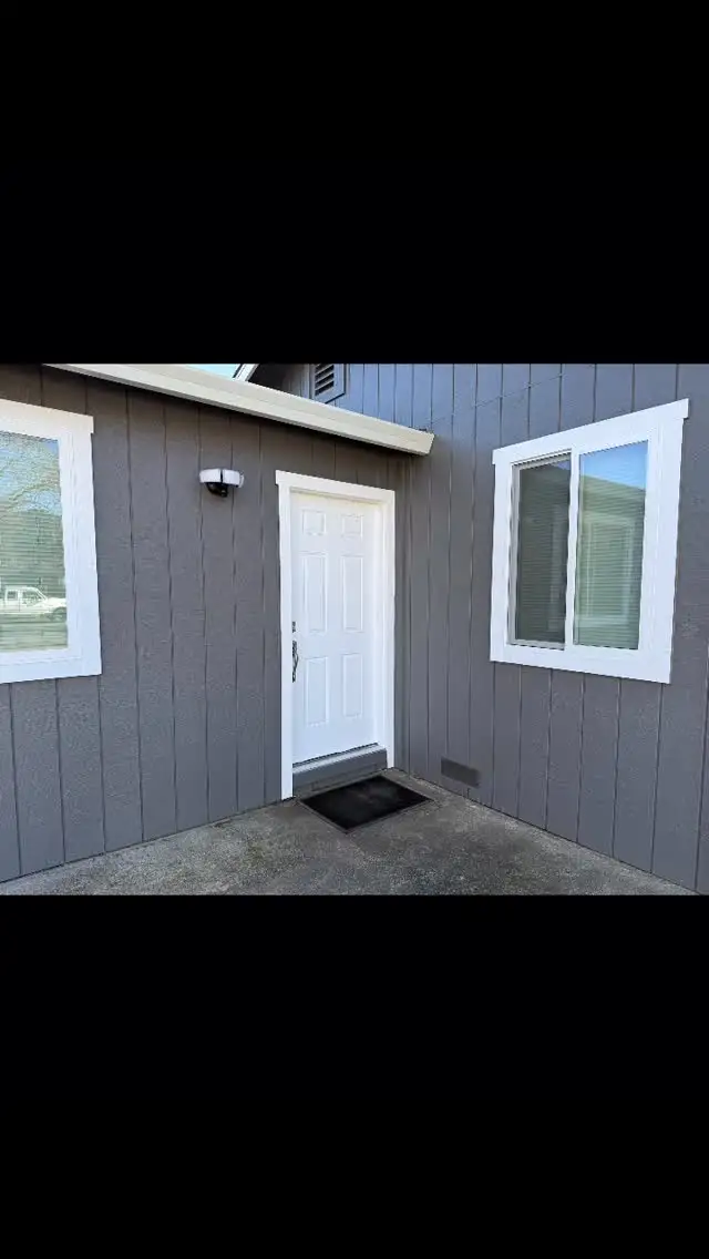 Santa Rosa home exterior corner with new gray siding, white trim, entry door, and windows opening onto a concrete patio