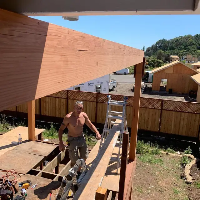 Builder installing timber post and beam for a pergola frame atop an elevated deck in Santa Rosa