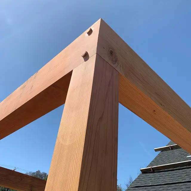 Redwood post-and-beam pergola frame with mitered beam joints under construction over a Santa Rosa deck