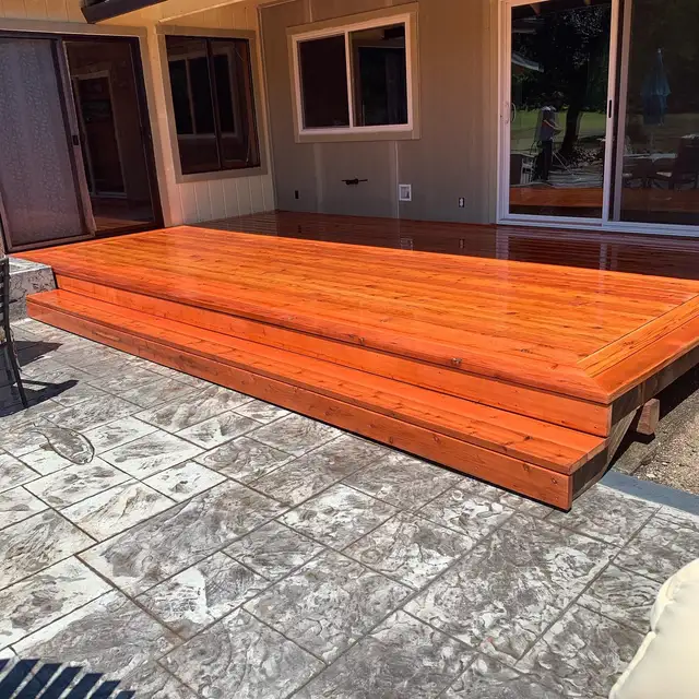 Low-profile redwood deck with double picture-frame border and wide steps beside stamped concrete patio in Santa Rosa