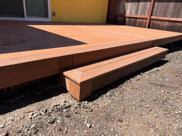 Low-profile TimberTech composite deck with two-tone board pattern and wide step down to gravel yard in Sonoma County