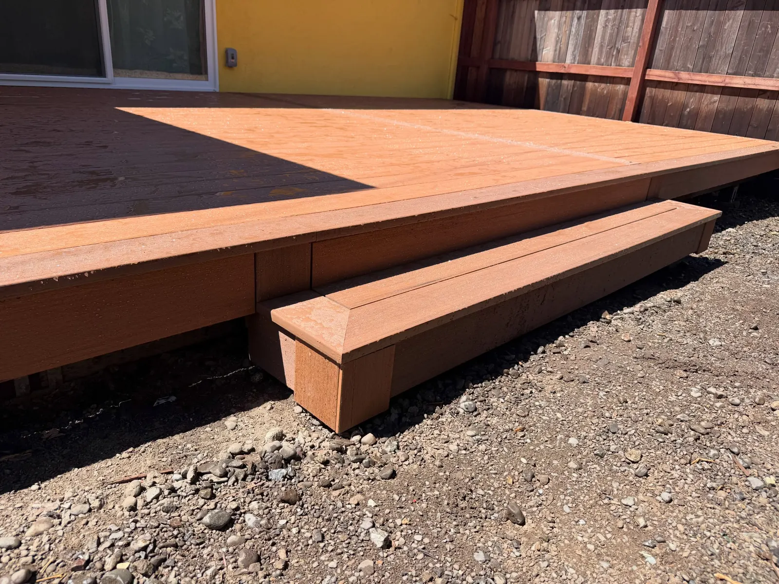 Low-profile TimberTech composite deck with two-tone board pattern and wide step down to gravel yard in Sonoma County