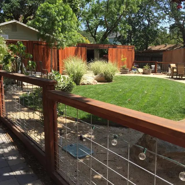 Redwood and hog-wire fence with sliding barn gate around a Sonoma backyard with circular lawn and decomposed granite