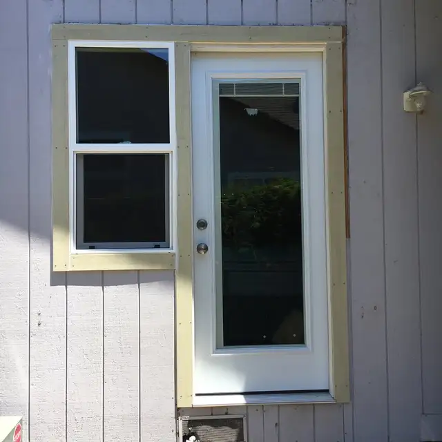 New vinyl double-hung window and glass panel exterior door installed in a fresh wood-framed opening in Windsor